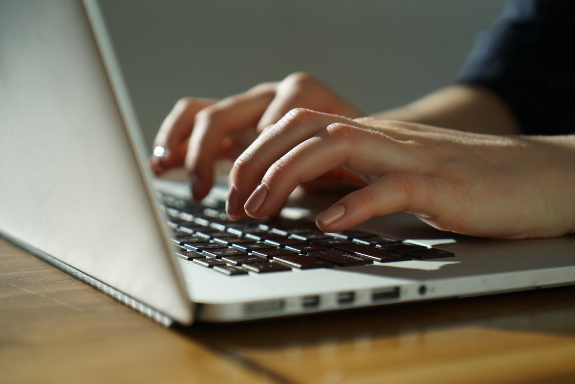 Close-up of hands typing on a laptop keyboard
